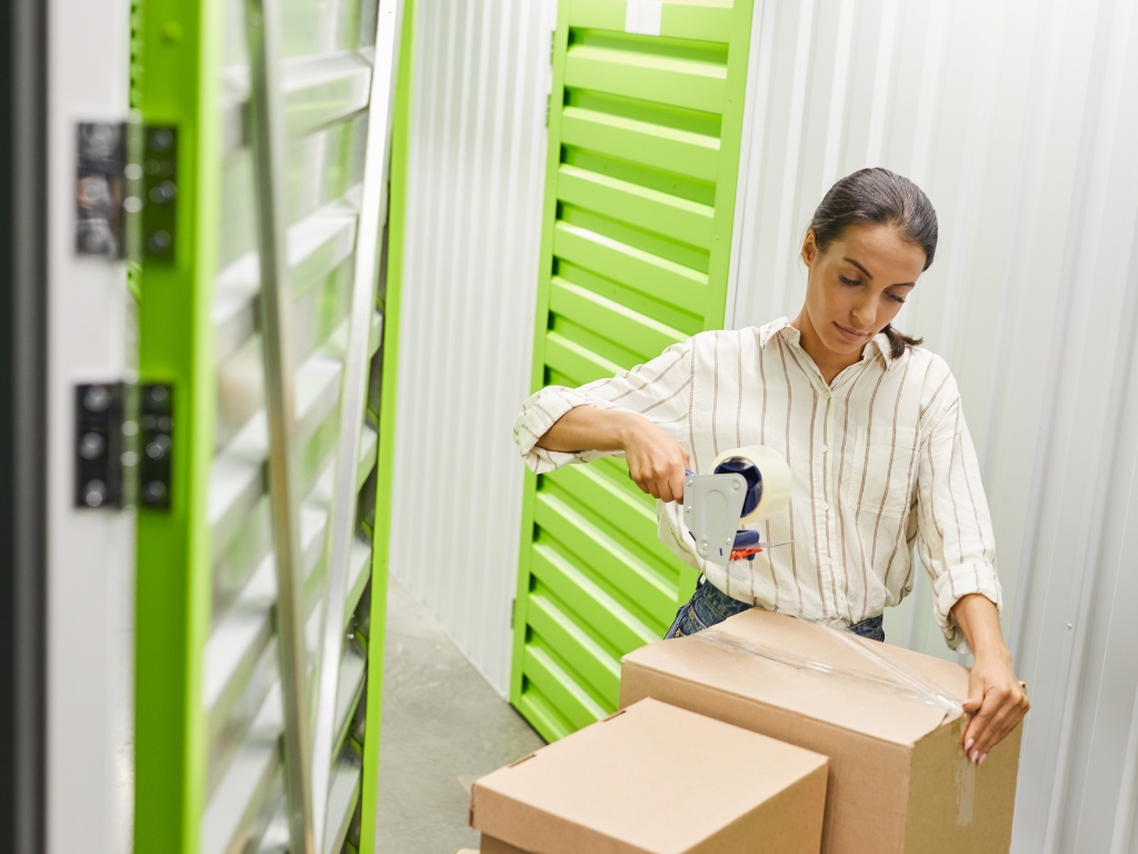 A woman carefully placing boxes into a self-storage unit, optimizing her space for better organization.