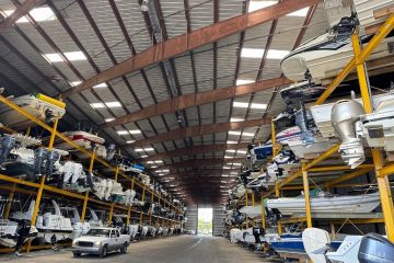 Inside a large warehouse, various boats are arranged on racks, highlighting efficient car storage for marine vehicles.