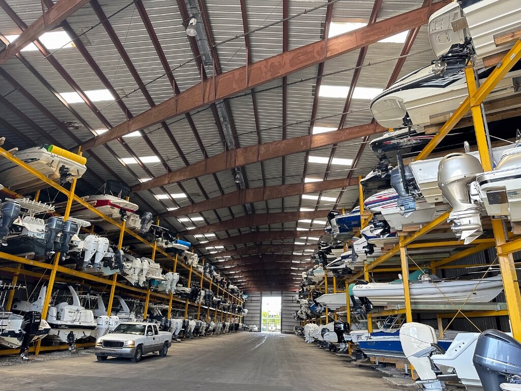 Inside a large warehouse, various boats are arranged on racks, highlighting efficient car storage for marine vehicles.